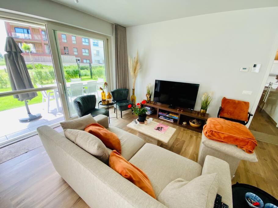 uma sala de estar com um sofá e uma televisão de ecrã plano em Luxury apartment "Volmolen" with garden, terrace and free parking em Harelbeke