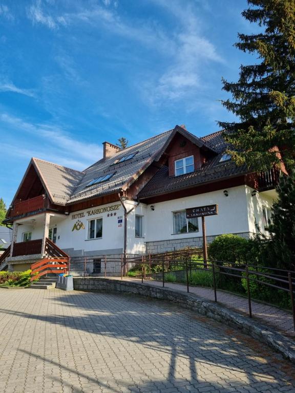 ein großes weißes Haus mit braunem Dach in der Unterkunft Hotel Karkonosze in Karpacz