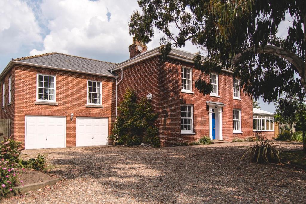 a brick house with two white garage doors at Church Farm Winterton-on-sea in Winterton-on-Sea