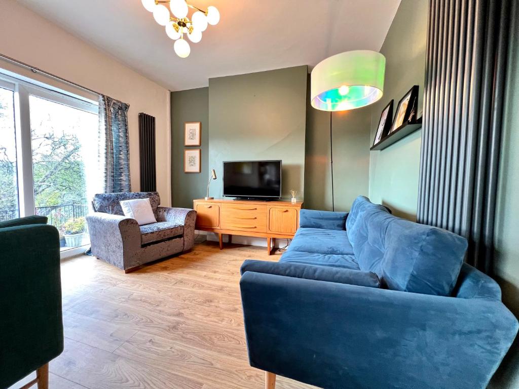 a living room with a blue couch and a tv at Brecon View by Switchback Stays in Newport