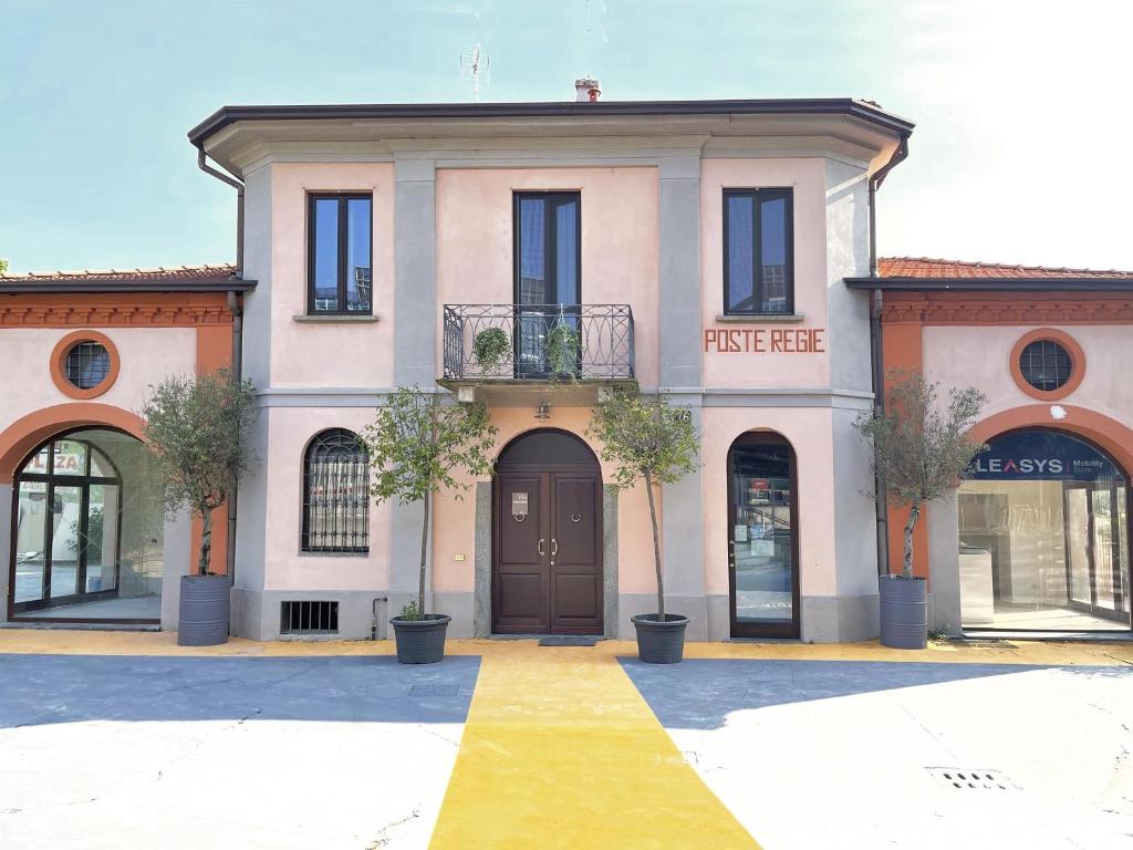 uma casa cor-de-rosa com árvores à frente. em Poste Regie - Milan Guest House em Milão