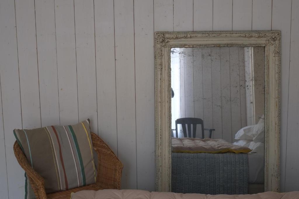 a mirror in a room with a bed and a chair at Hôtel Le Sénéchal in Ars-en-Ré