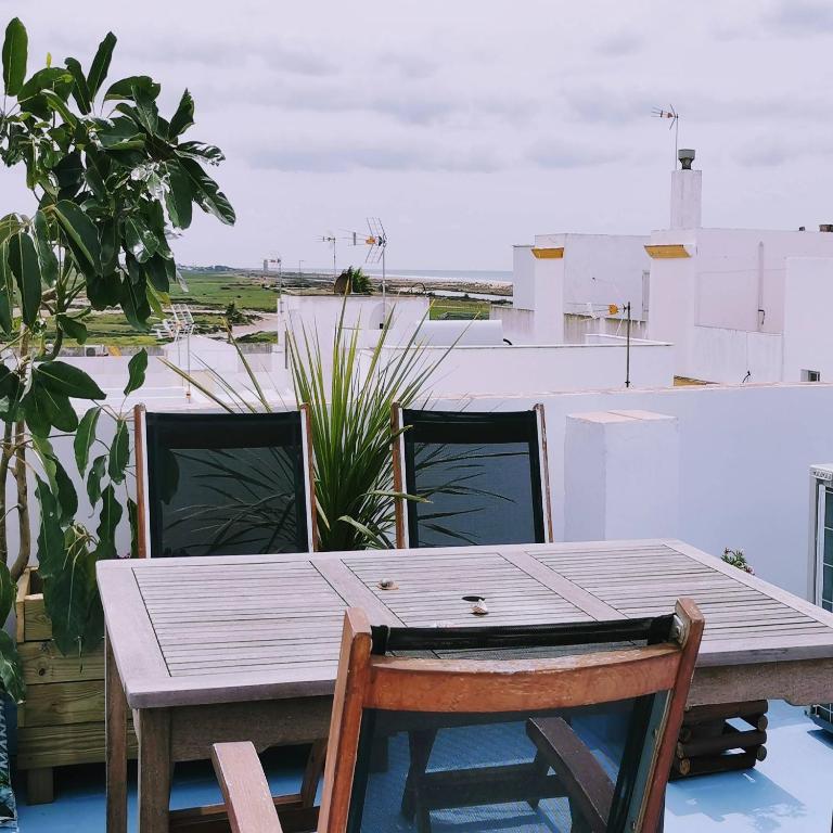 a wooden table and chairs on top of a roof at ABA DALÍ in Conil de la Frontera
