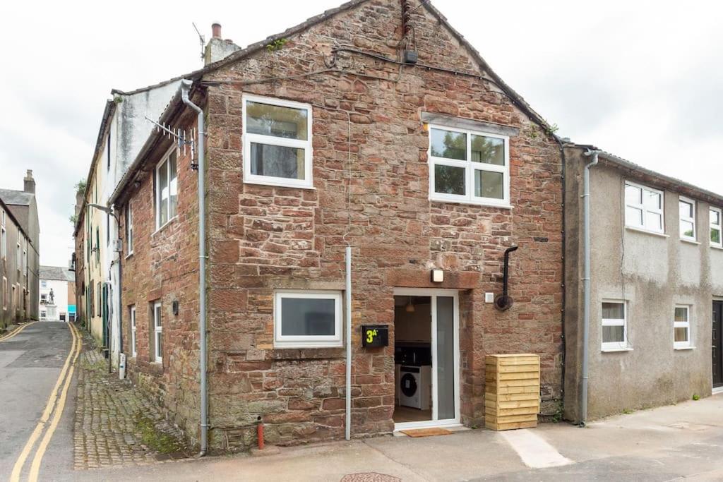 an old brick building with a door on a street at Milo's place is a home from home in Egremont