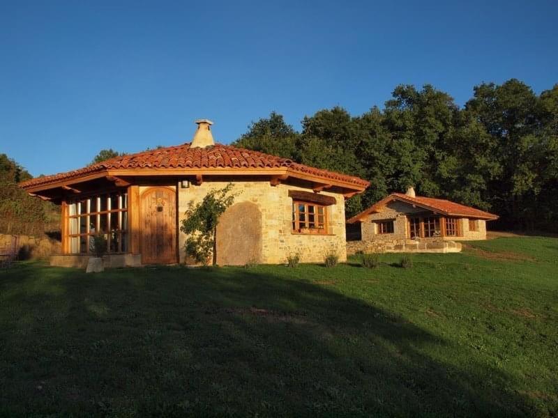 a small house in a grassy field with a building at Guikuri Octogono casa rural 1, 2 y 3pax in Múrua