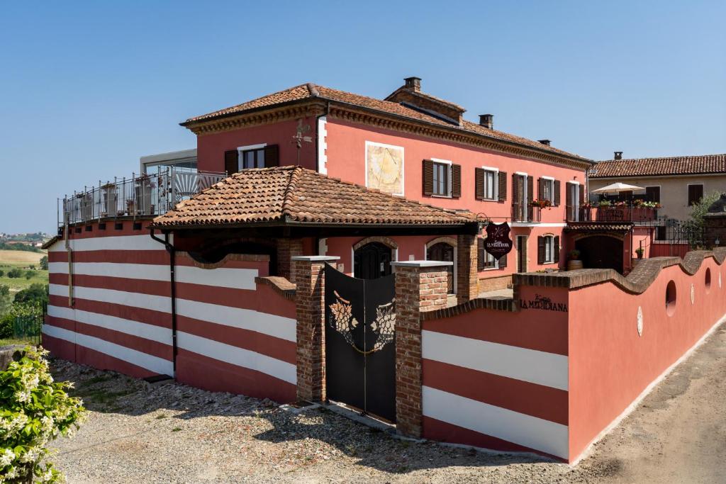 une maison rouge et blanche avec un portail et une clôture dans l'établissement Agriturismo Tenuta La Meridiana, à Montegrosso dʼAsti