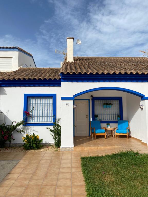 Casa blanca con sillas azules y patio en Denia Playa III, en Denia