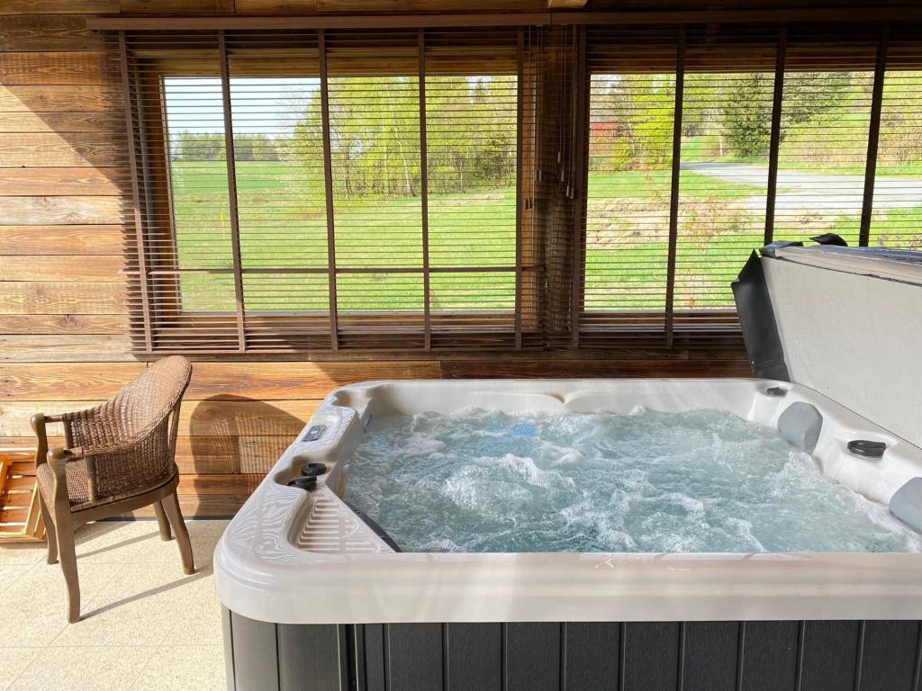 a hot tub in a room with a chair and windows at Frankenwald-Lodge in Schwarzenbach am Wald