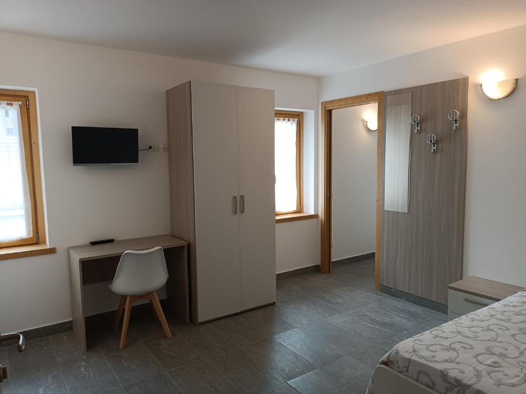 a bedroom with a bed and a desk and a cabinet at Gufo Depandance in Bormio