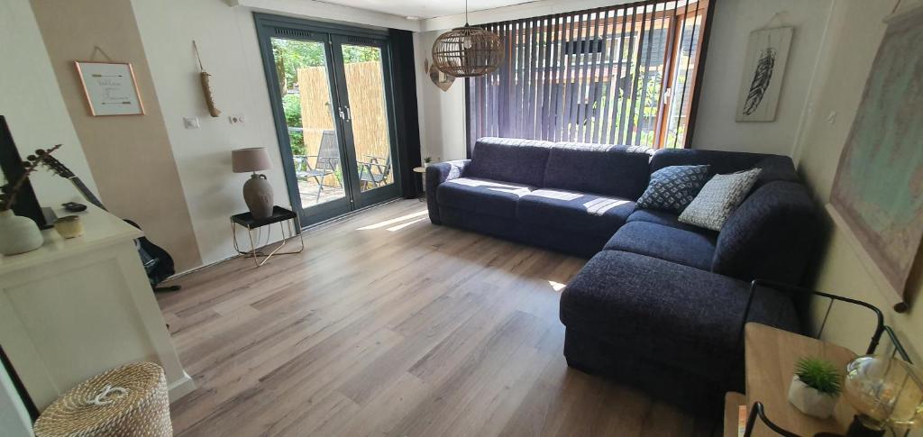 un soggiorno con divano blu e pavimenti in legno di Chalet 11, in het bos a Doornspijk