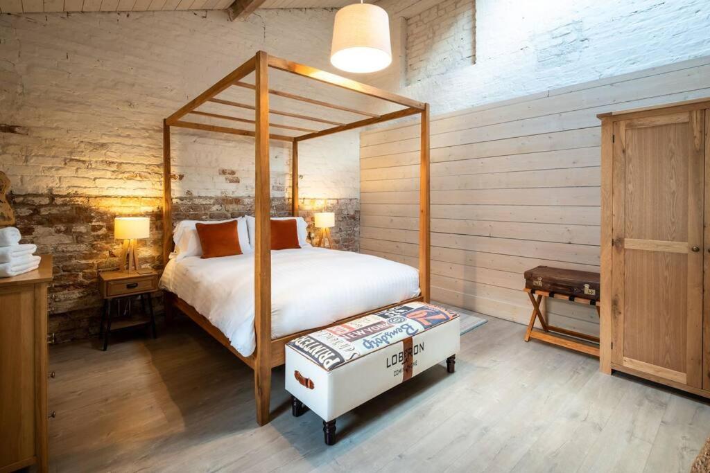 a bedroom with a canopy bed and a wooden wall at The Mews -- Luxury Stay at Bellingham Estate in Castlebellingham