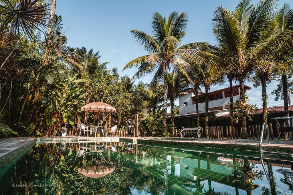 a swimming pool with palm trees and a building at Pousada e Hostel Marthi in Ubatuba