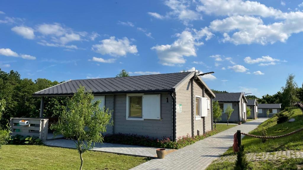 a small house in a yard with a driveway at Domki Letniskowe na Dzikiej in Tolkmicko