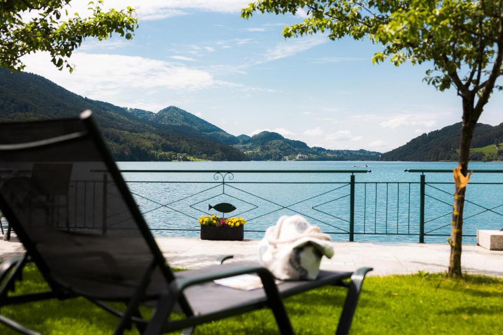 uma cadeira sentada na relva ao lado de um lago em Pension Antonia em Fuschl am See