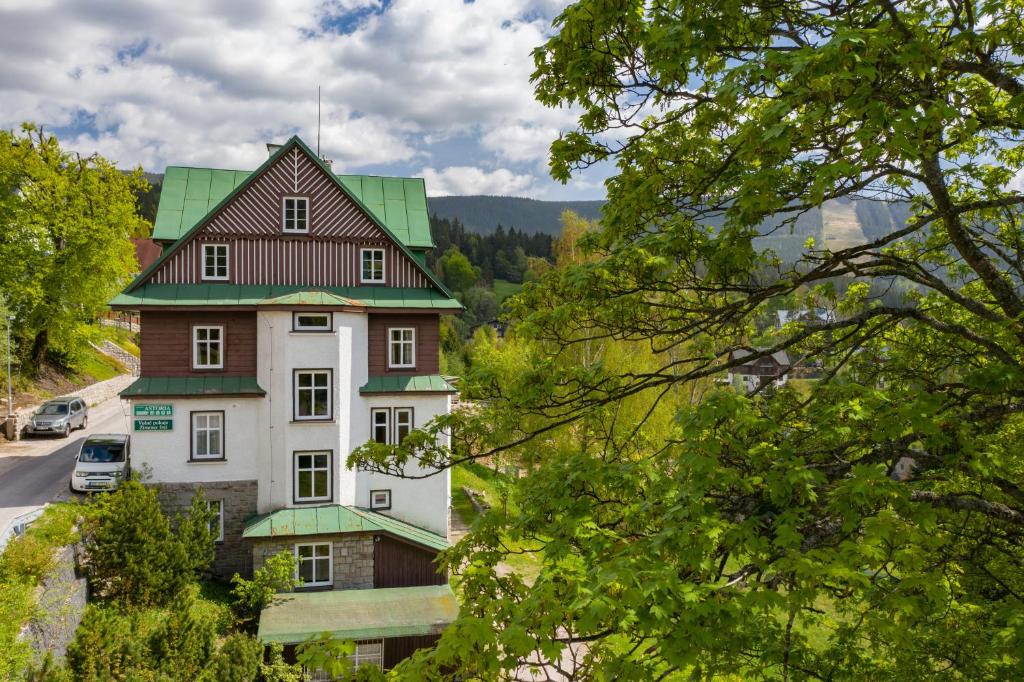 een groot wit huis met een groen dak bij Astoria Inn in Špindlerův Mlýn