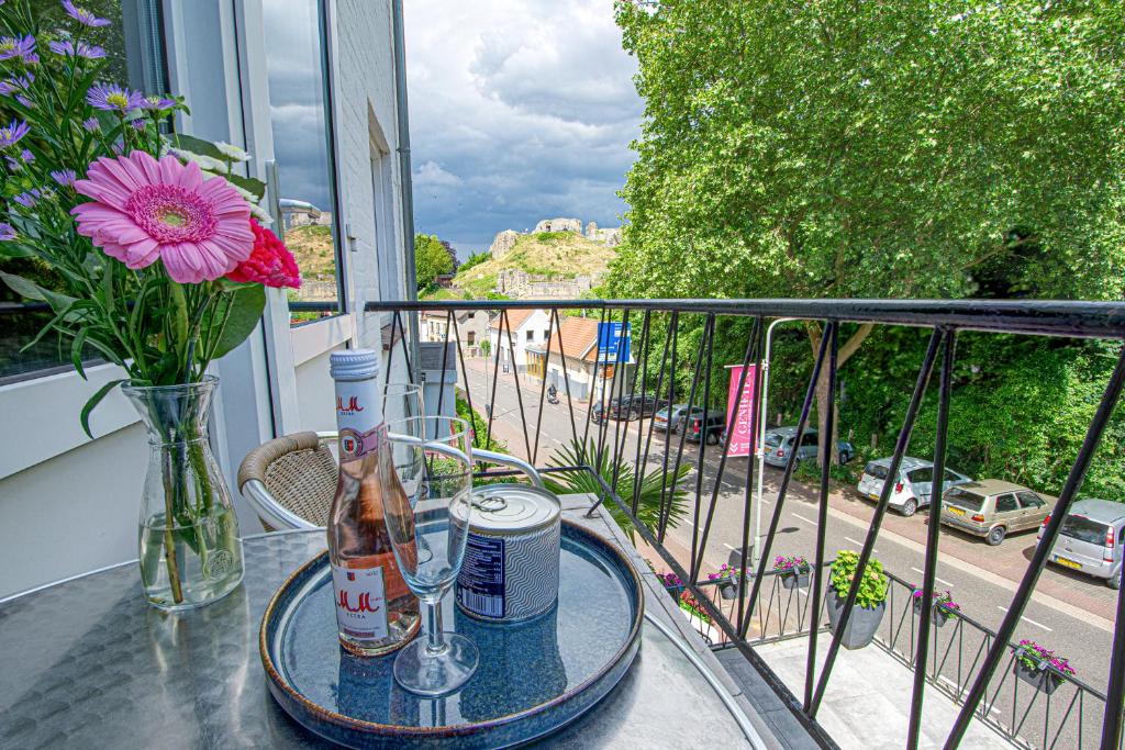 una mesa con una botella y un jarrón en el balcón en Logement viphouse Valkenburg, en Valkenburg