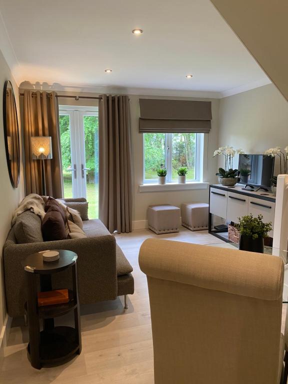 uma sala de estar com um sofá e uma mesa em Gleneagles Holiday Home em Auchterarder