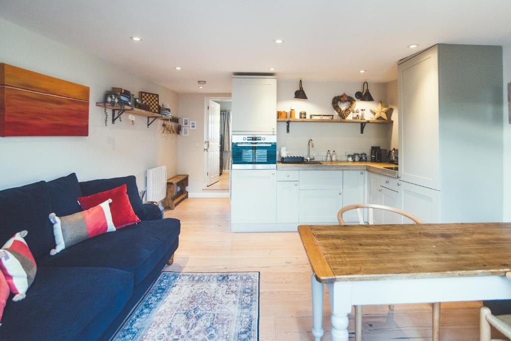 a living room with a blue couch and a kitchen at The Annexe - Stoke Fleming in Stoke Fleming