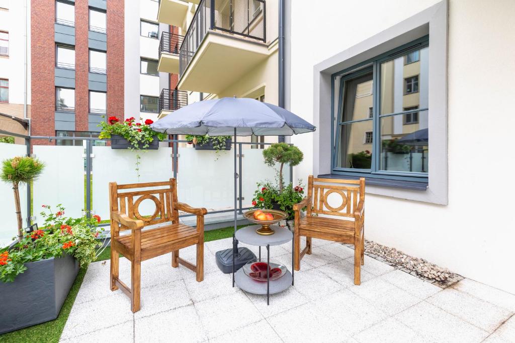 eine Terrasse mit 2 Stühlen und einem Tisch mit einem Sonnenschirm in der Unterkunft Bea Garden Home - dwie sypialnie i taras in Elblag