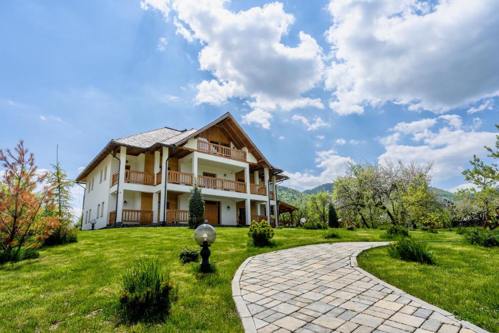 uma casa grande com um jardim relvado e uma passagem em Pensiunea Coronita em Vişeu de Sus