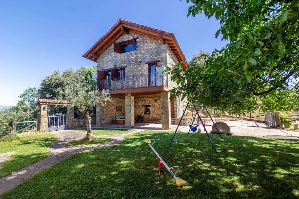 una casa con un árbol y un columpio en Casa Rural Tejedor, en Morillo de Monclús