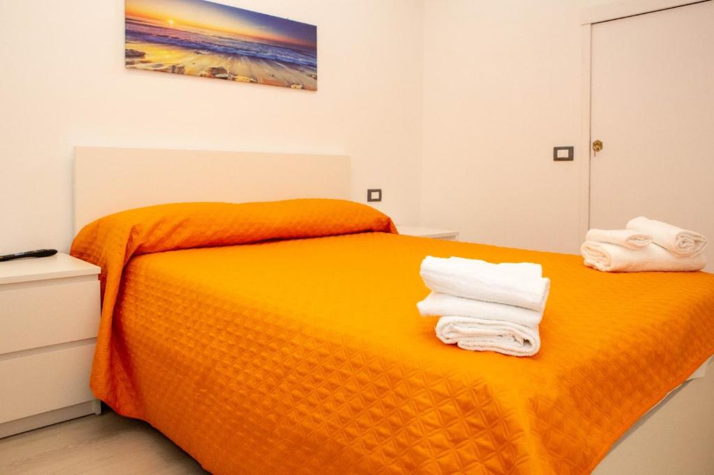 una camera da letto con un letto arancione e asciugamani di Endless Summer Apartment a Marina di Ragusa