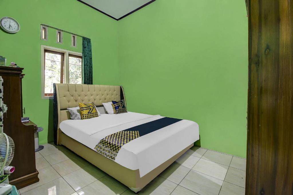 - une chambre avec un lit dans un mur vert dans l'établissement OYO Homes 91153 Desa Wisata Kawasen, à Padaherang