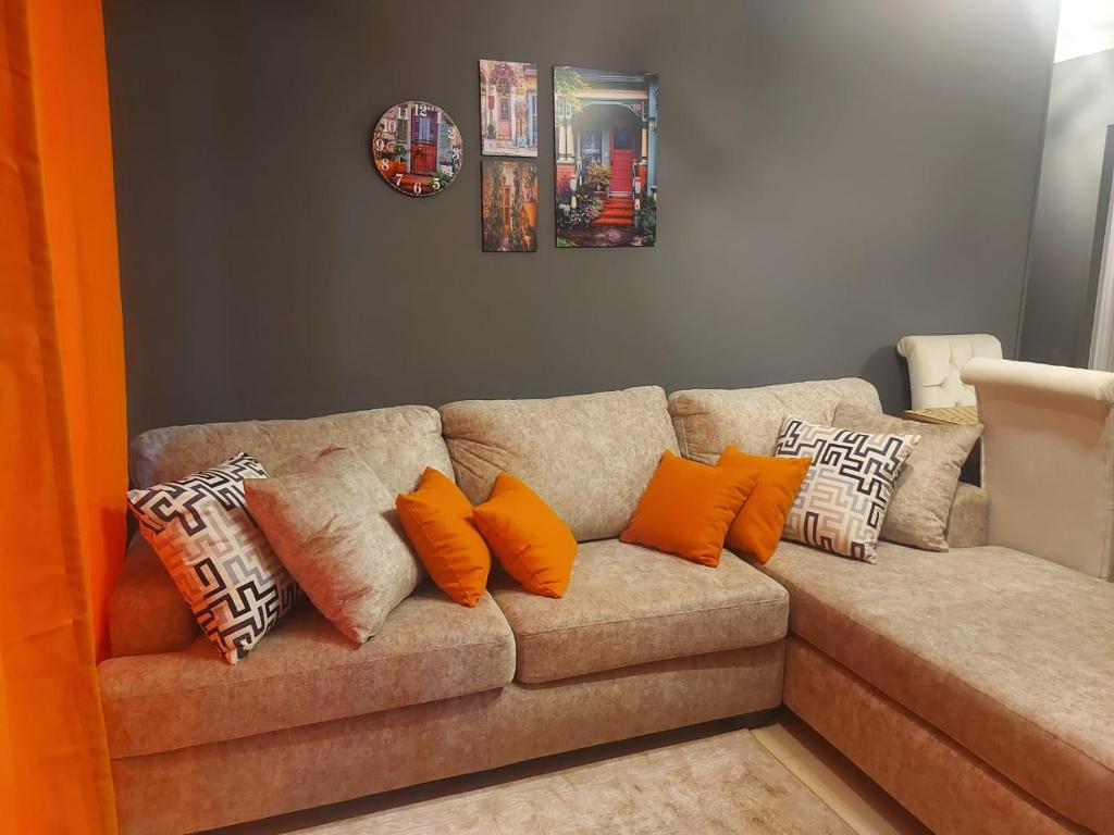 a living room with a couch with orange pillows at Trendy House in Badr