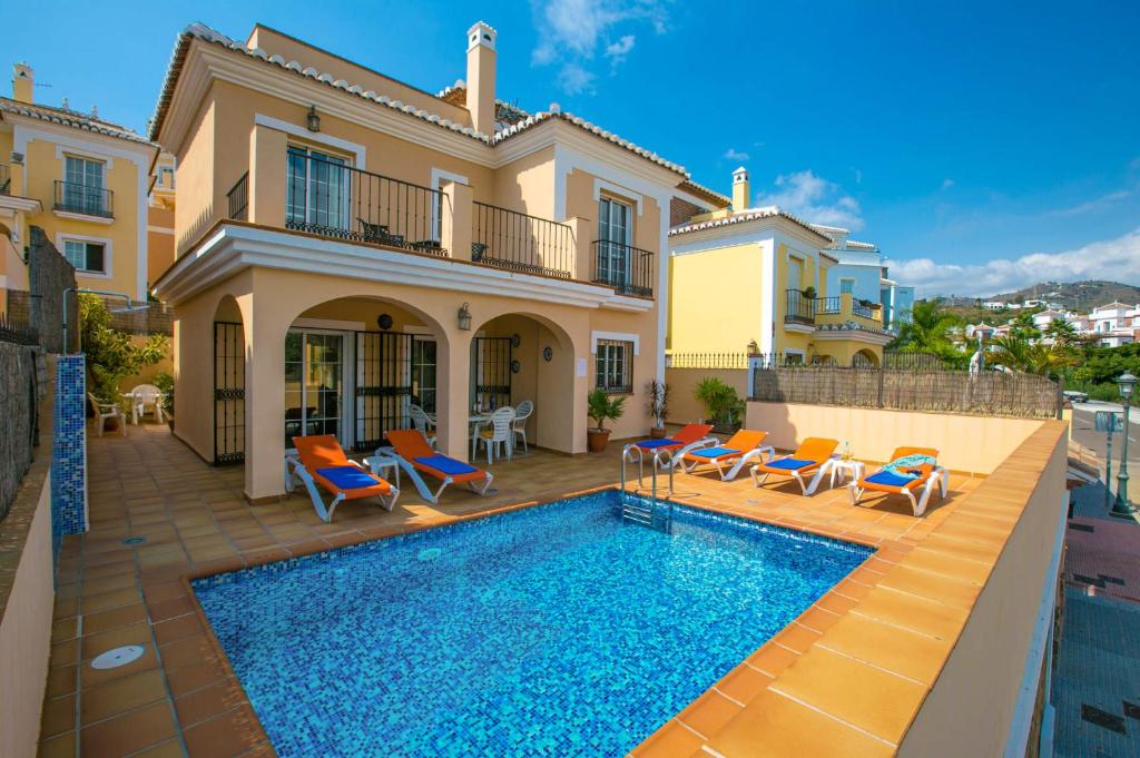 a villa with a swimming pool in front of a house at Villa Reyes in Nerja