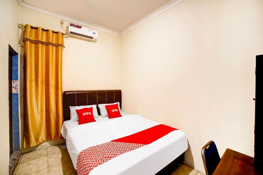a bedroom with a bed with red pillows at OYO 91199 Felicia Homestay in Medan