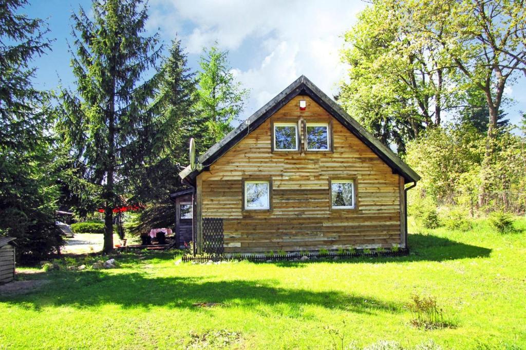 una pequeña casa de madera en un campo de hierba en holiday home, Wilimy en Wilimy