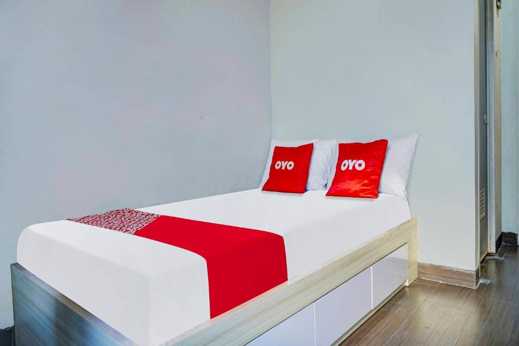 a white bed with two red pillows on it at OYO Life 91205 Rindang Guesthouse Syariah in Karawang