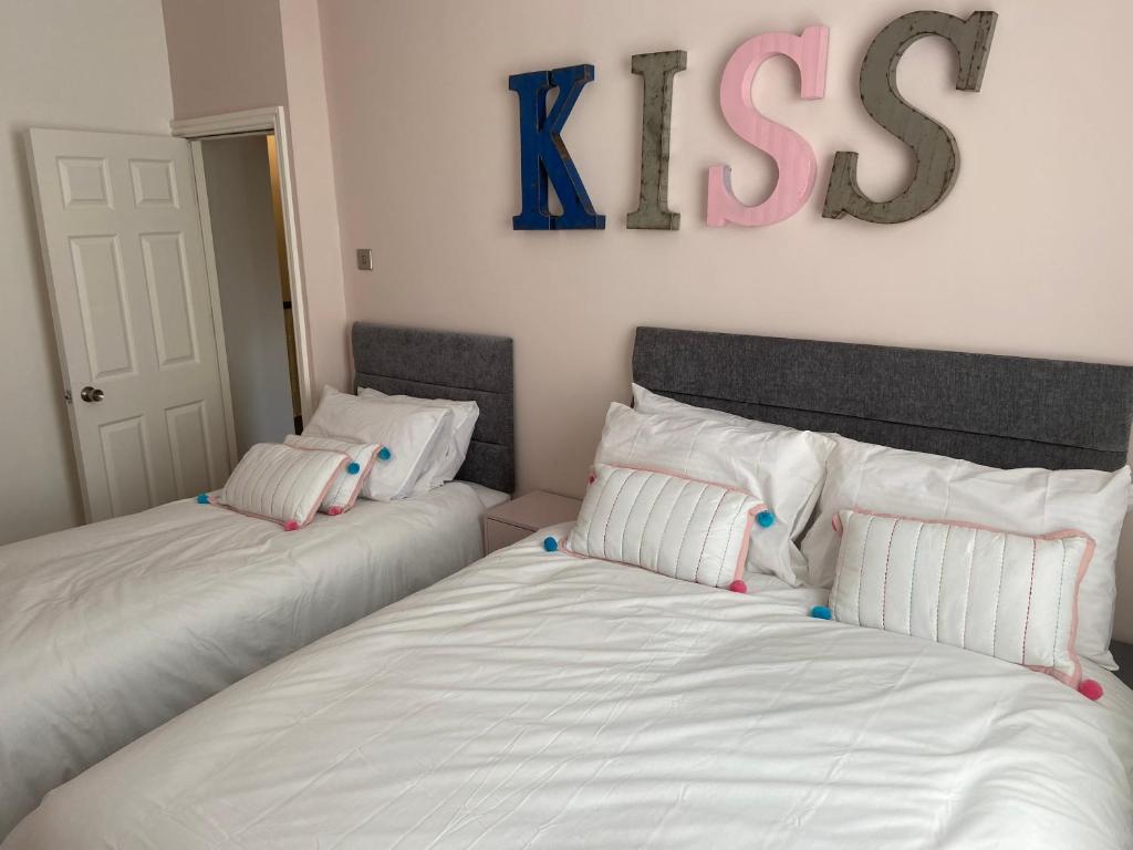 2 Betten in einem Zimmer mit einem Kussschild an der Wand in der Unterkunft RELAX Blackpool in Blackpool