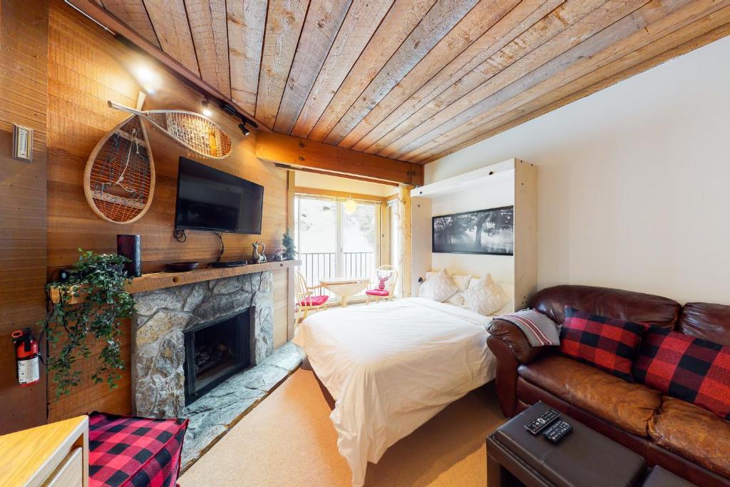 ein Wohnzimmer mit einem Bett und einem Kamin in der Unterkunft Moguls 813 in Big White