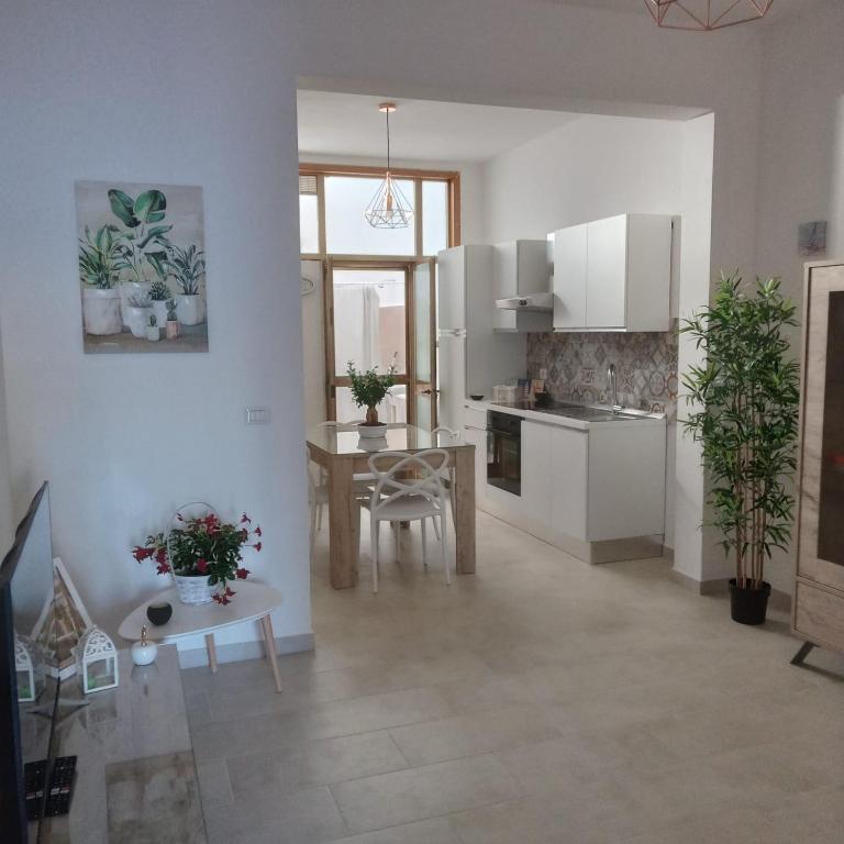una cocina con armarios blancos y una mesa con plantas en Casa Angelina Summer, en Casalabate