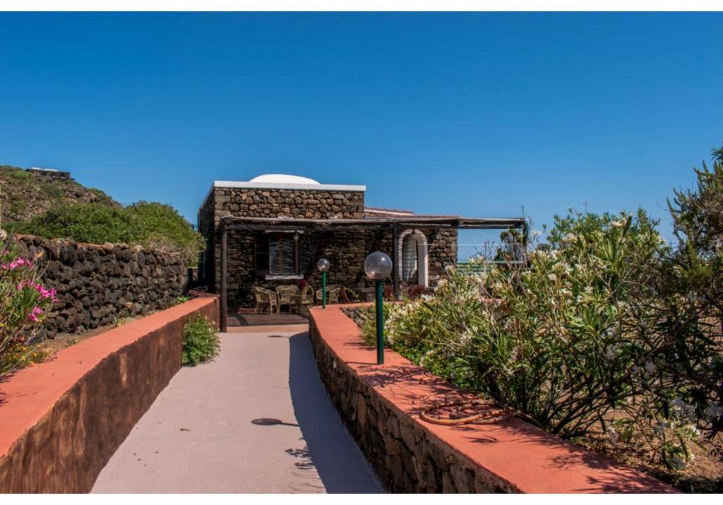 einen Gehweg, der zu einem Gebäude mit einer Steinmauer führt in der Unterkunft Dammuso bougainville in Pantelleria