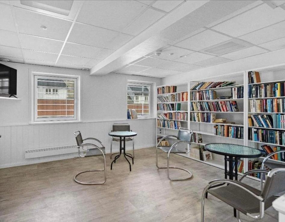biblioteca con 2 tavoli, sedie e librerie di Fengselshotellet i Arendal ad Arendal
