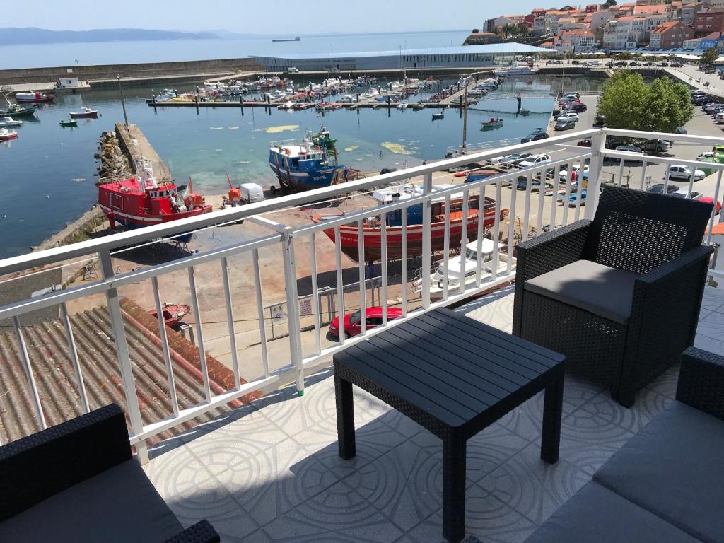 un balcón con 2 sillas, una mesa y un puerto en Apartamento vista al Puerto de Finisterre, en Finisterre