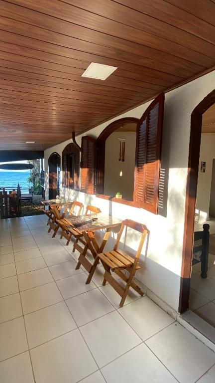 un grupo de mesas y sillas de madera en un edificio en • Suíte Palmas • À Beira-Mar - Ilha Grande RJ®, en Praia de Palmas