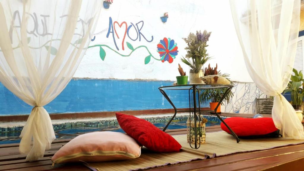 a room with red pillows on a bench with a window at Ho'oponopono Hostel in Caraguatatuba