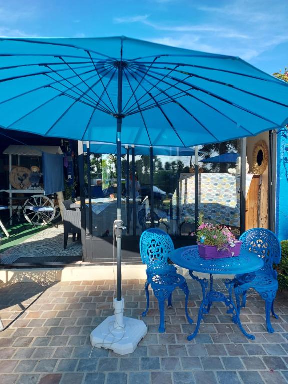 une table bleue avec deux chaises et un parapluie bleu dans l'établissement Le paradis bleu, à Bosville