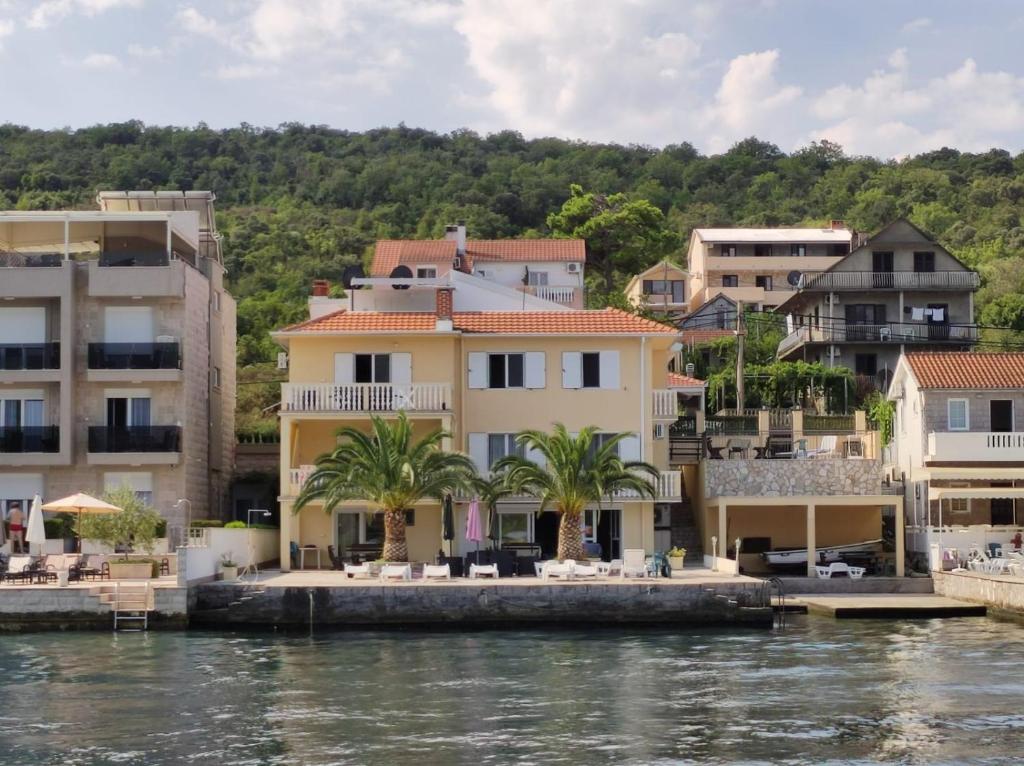a group of houses on the water with palm trees at un site calme et unique au Montenegro Loue des logements les pieds dans l eau avec plage privée en face de l ile Saint Marco in Tivat