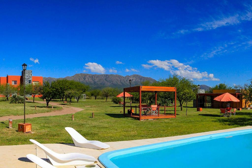 una piscina con sillas y un cenador junto a un campo en Cabañas Portal Uritorco en Capilla del Monte