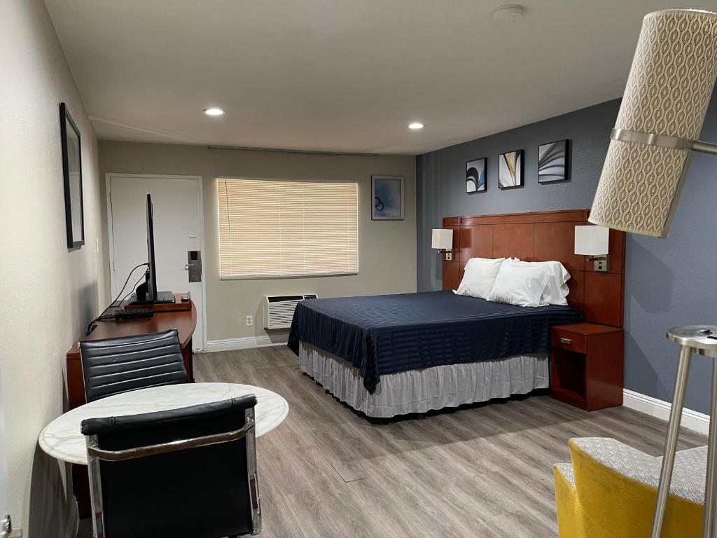 a bedroom with a bed and a table and a chair at Bel Air Motor Hotel in Tustin
