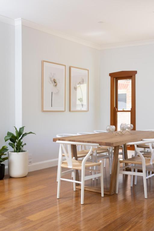 a white dining room with a wooden table and chairs at Kuzman Homestead in Mudgee