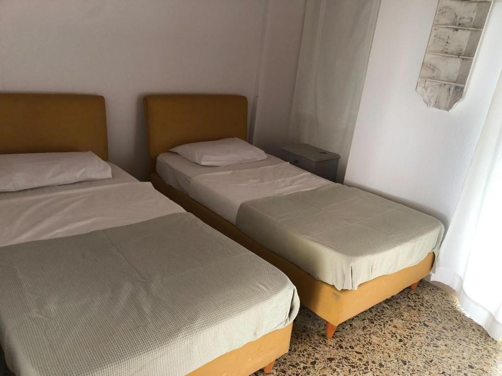 two twin beds in a room with a window at LaLuzaki in Spetses