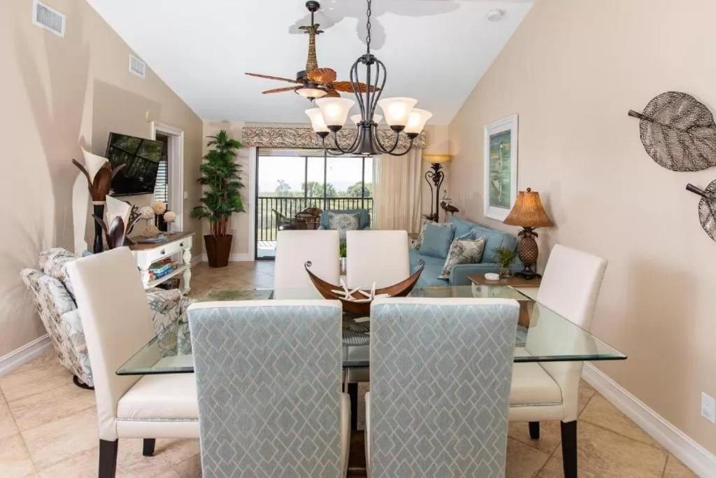 a dining room with a glass table and white chairs at SANDPIPER BEACH 205 in Sanibel