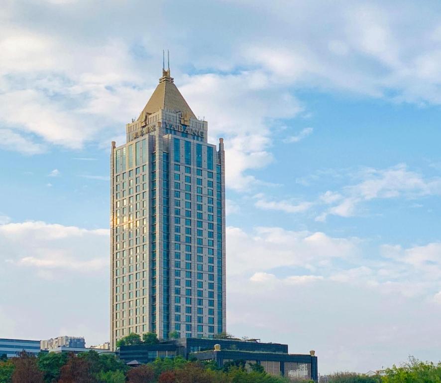 wysoki wieżowiec z dachem na górze w obiekcie Shenzhen LANGYUE International Hotel w mieście Longgang