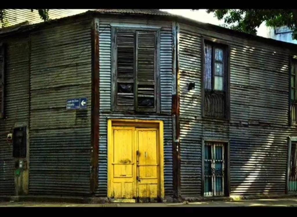 een oud houten gebouw met een gele deur bij Monoambiente en La Boca. in Buenos Aires