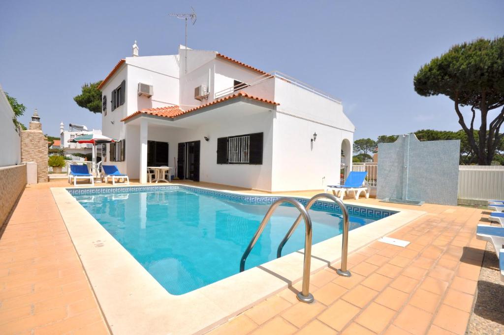 a villa with a swimming pool and a house at Spacious 4 bedroom villa located in its own grounds, with private pool and Bbq.. in Quarteira
